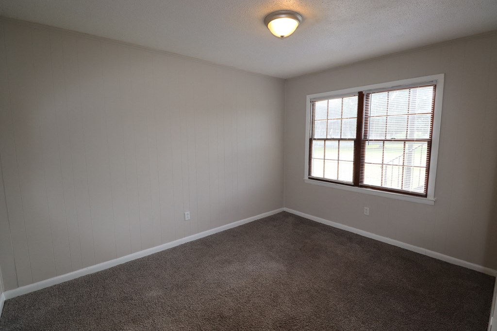 an empty living room with a window and carpet