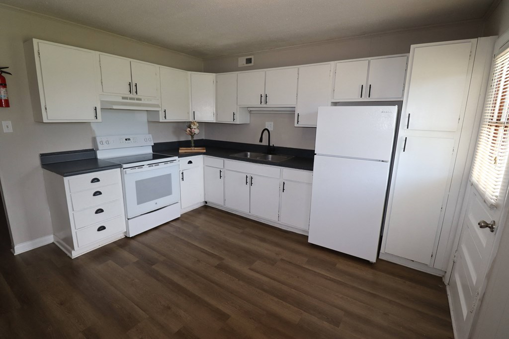 a kitchen with white cabinets and a white stove and refrigerator