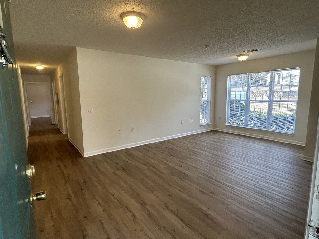 an empty living room with wooden floors and a large window