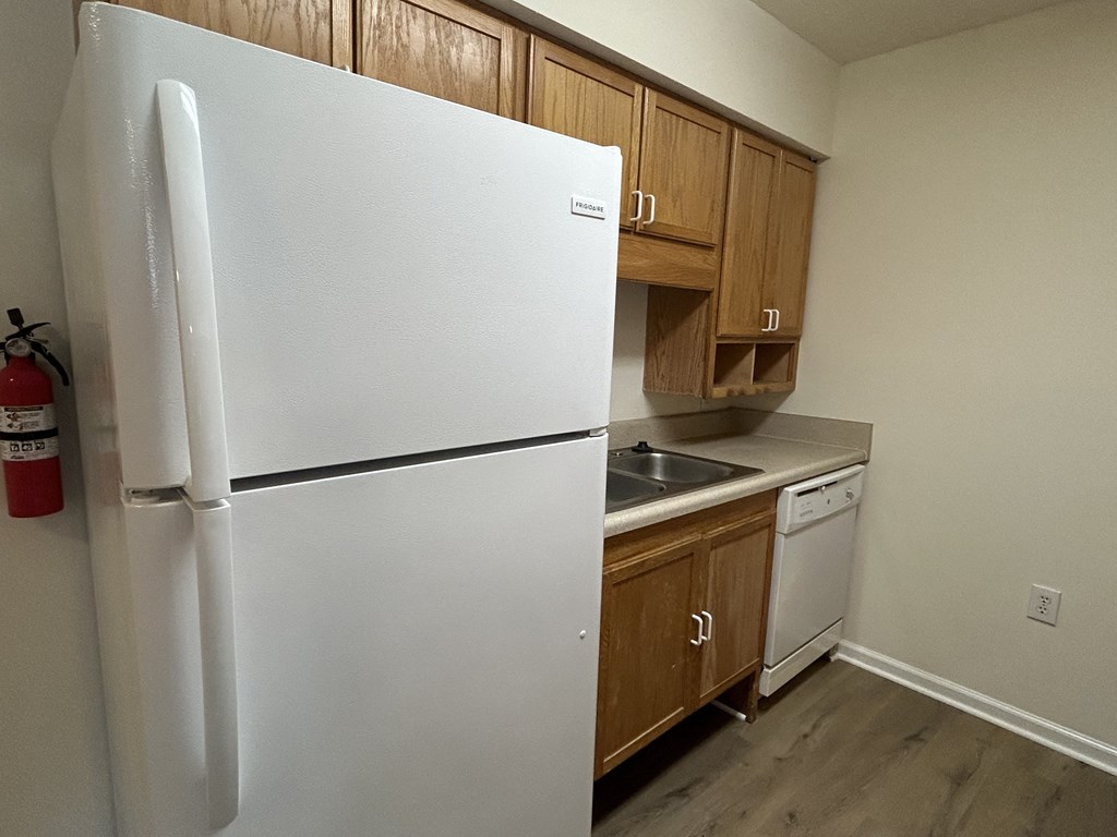 a kitchen with a white refrigerator and wooden cabinets