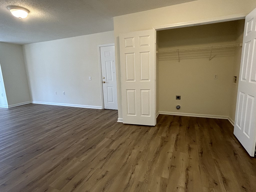 an empty living room with wood flooring and a closet