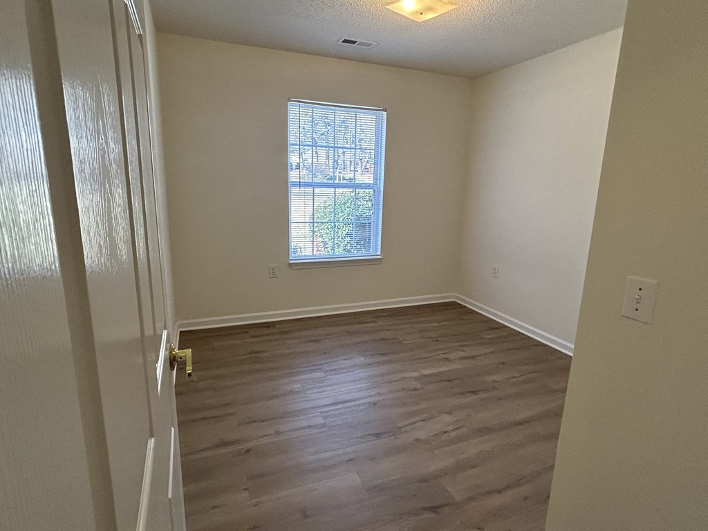 an empty room with wooden floors and a window