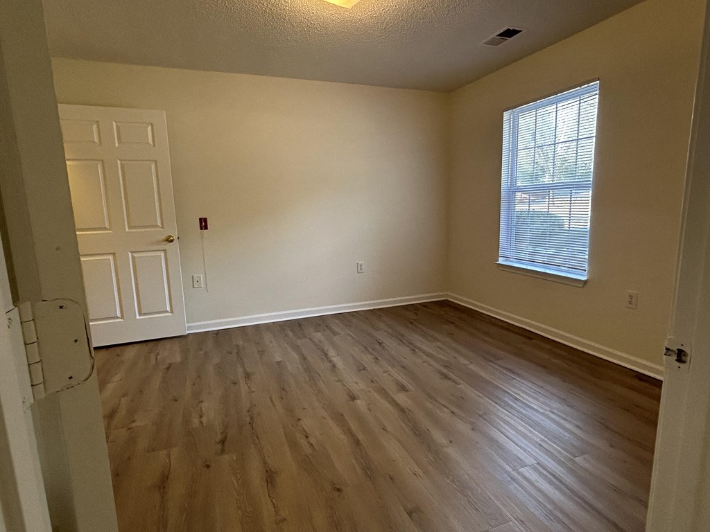an empty living room with wooden floors and a window