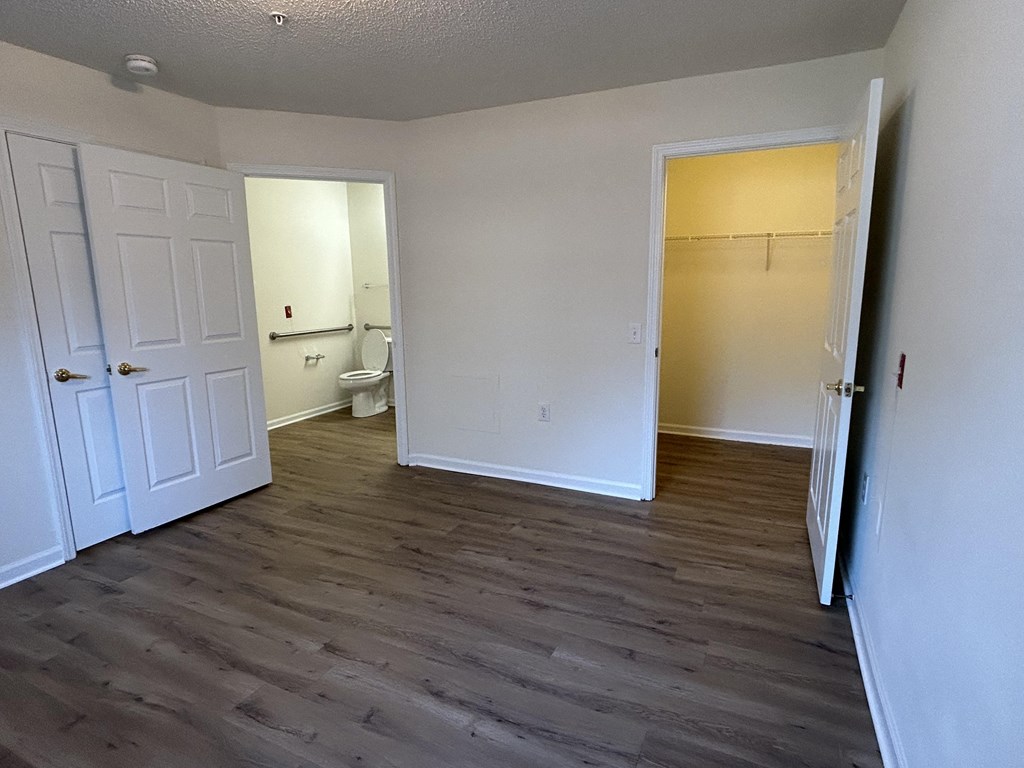an empty living room with wood flooring and a bathroom