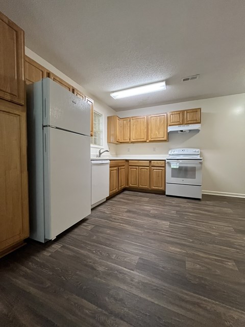 A kitchen with a white refrigerator and a white dishwasher.