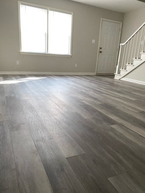 a living room with a hardwood floor and a staircase