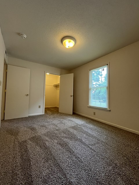 A room with a carpeted floor and a window.