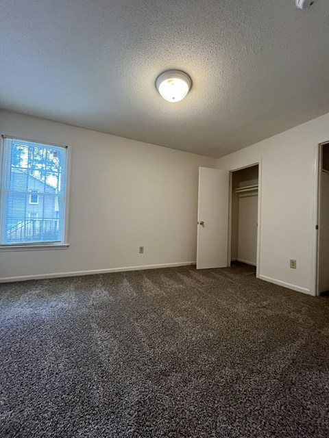 A room with a carpeted floor and a window.