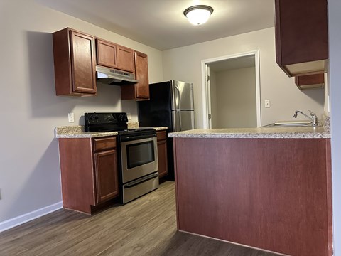 A kitchen with a black refrigerator and stove top oven.