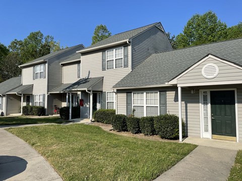 A row of houses with green lawns in front.