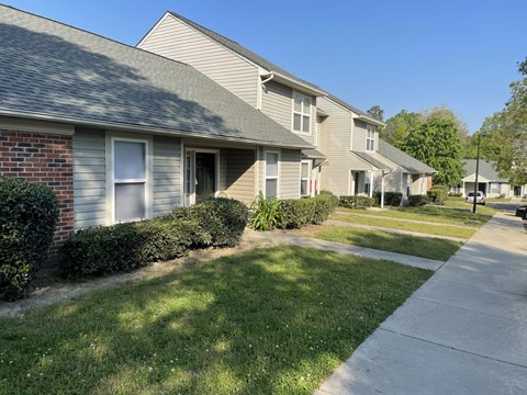 A row of houses with a sidewalk in front.