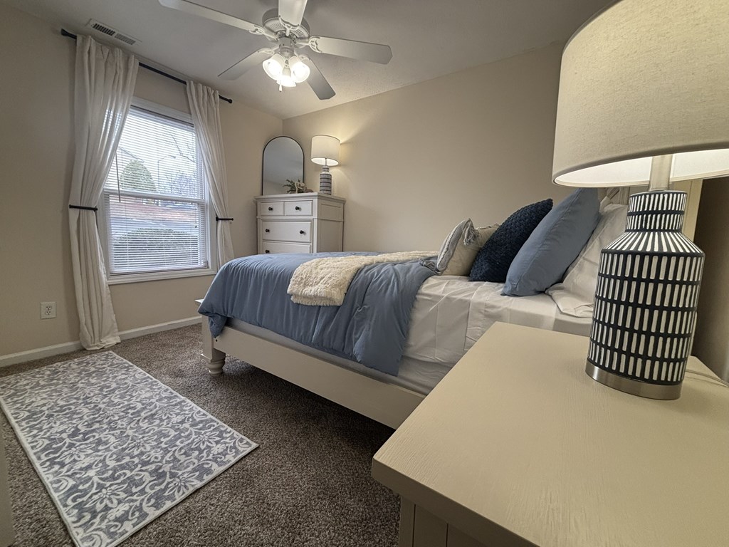 A bedroom with a bed, dresser, and window.