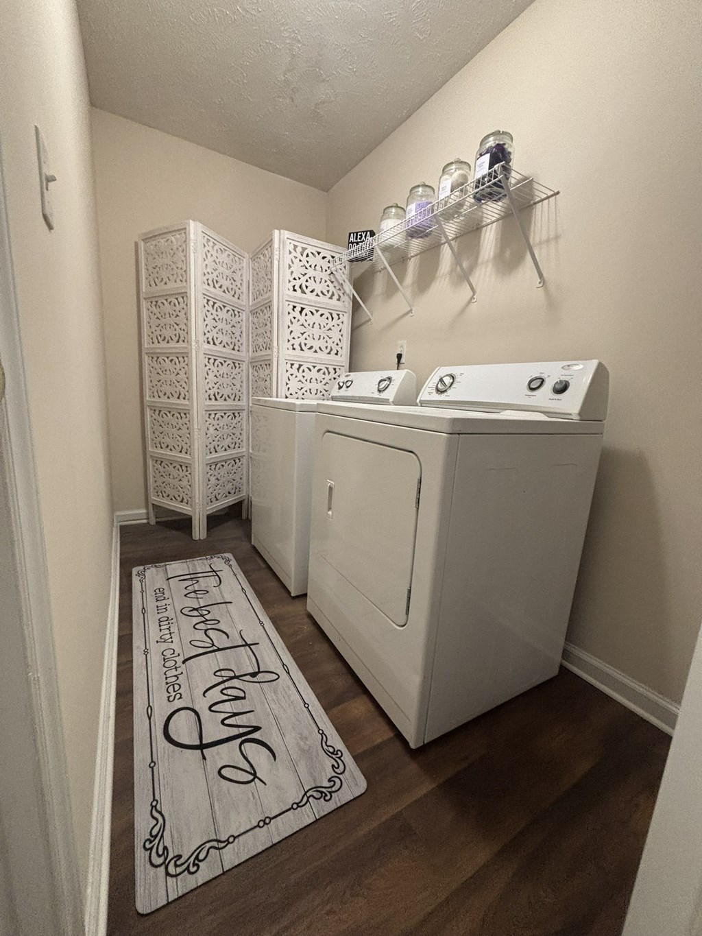 A laundry room with a washer and dryer and a rug on the floor that says "Happy Laundry Days".