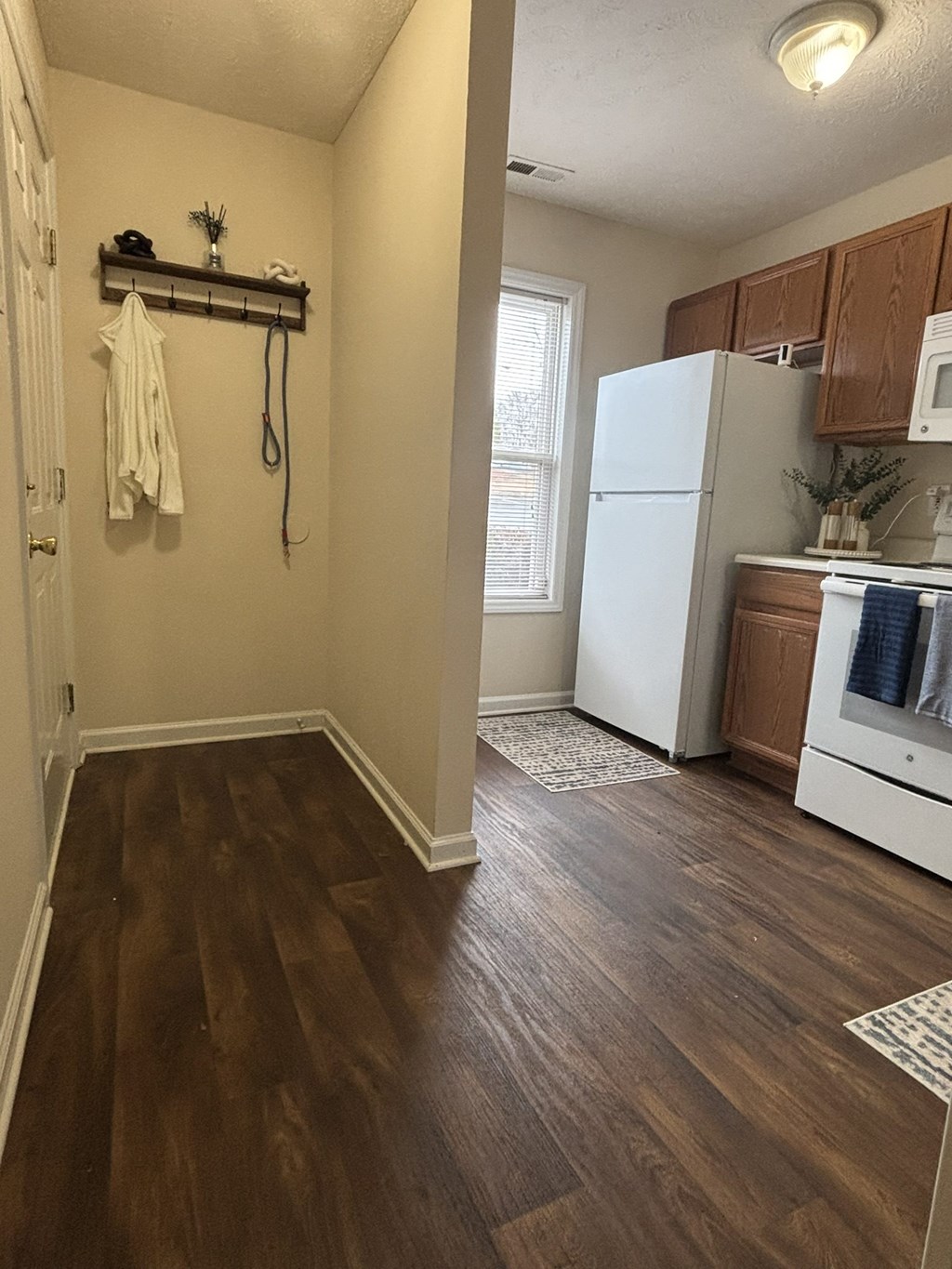 A white refrigerator is in a kitchen with wood floors.