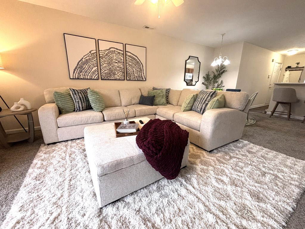 A living room with a white couch and a red throw on the ottoman.