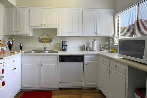 A kitchen with white cabinets and appliances.