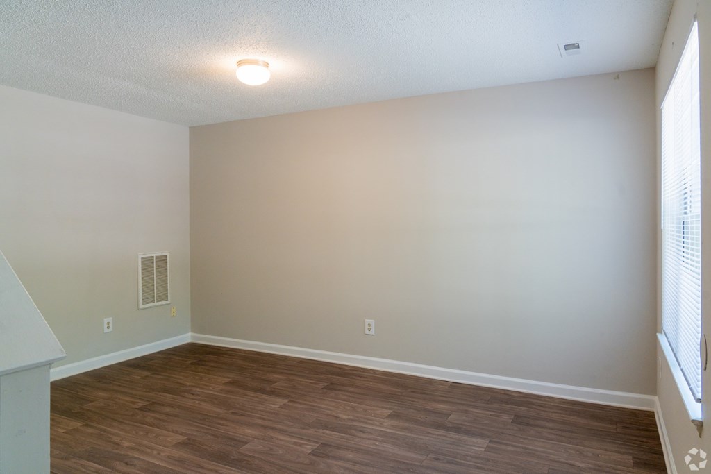 A room with wooden flooring and a window on the right side.