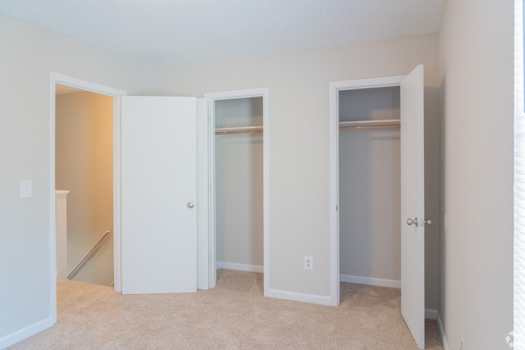 Three white closet doors are open in a room.