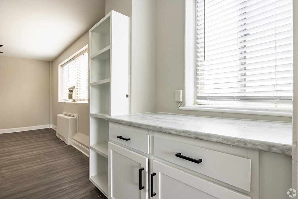 a kitchen with white cabinets and a window