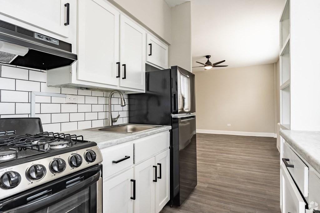a kitchen with white cabinets and black appliances