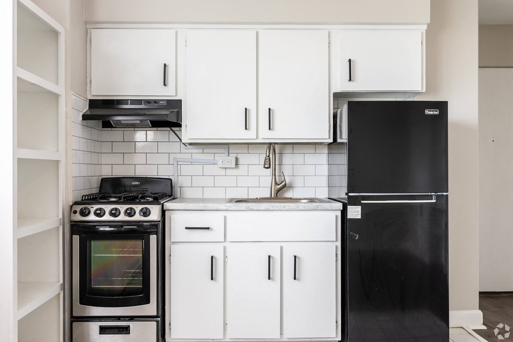 a kitchen with white cabinets and black appliances