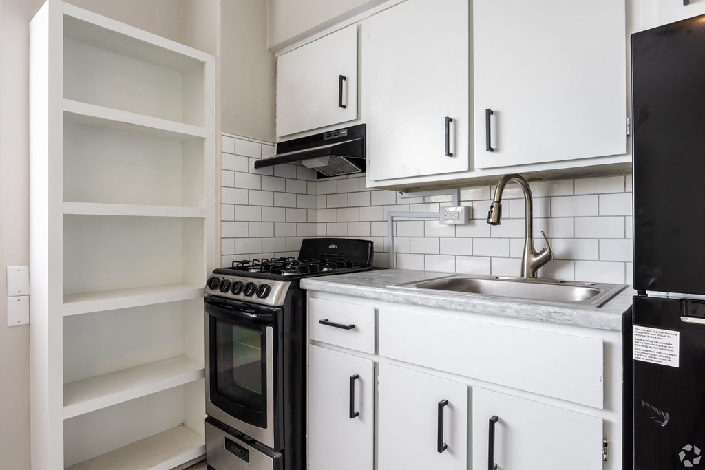 a kitchen with white cabinets and black appliances