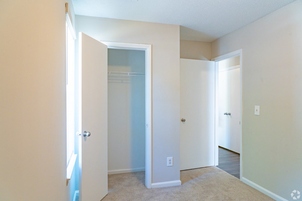 A room with a carpeted floor and a doorway leading to another room.