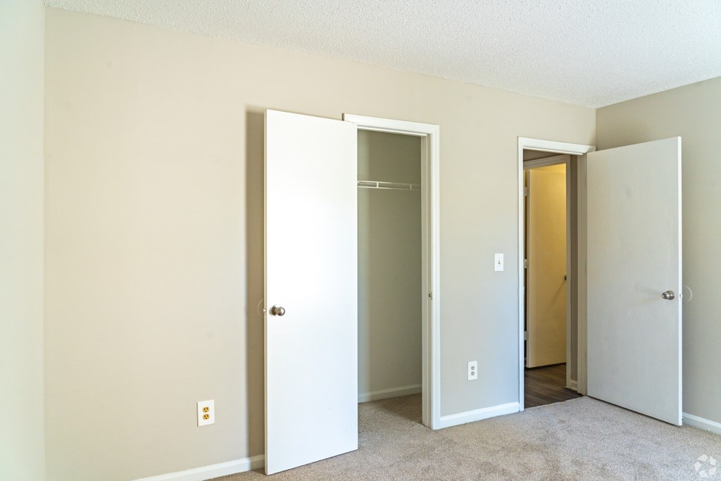 Three white doors in a room with carpeted floor.