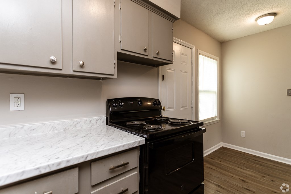 an empty kitchen with white cabinets and a black stove