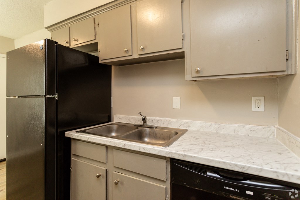 an empty kitchen with a sink and a refrigerator