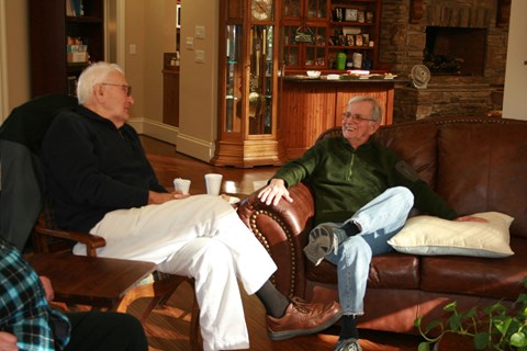 Two men sitting on a couch in a living room.
