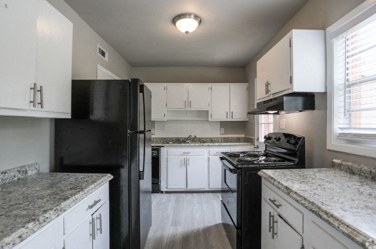 a kitchen with white cabinets and a black refrigerator