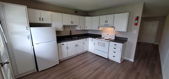 a kitchen with white cabinets and appliances and wood floors