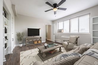 a living room with a ceiling fan and a tv