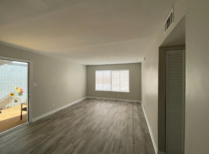 an empty living room with wood floors and a window
