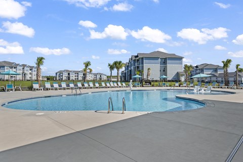 A large swimming pool with a slide and a building in the background.