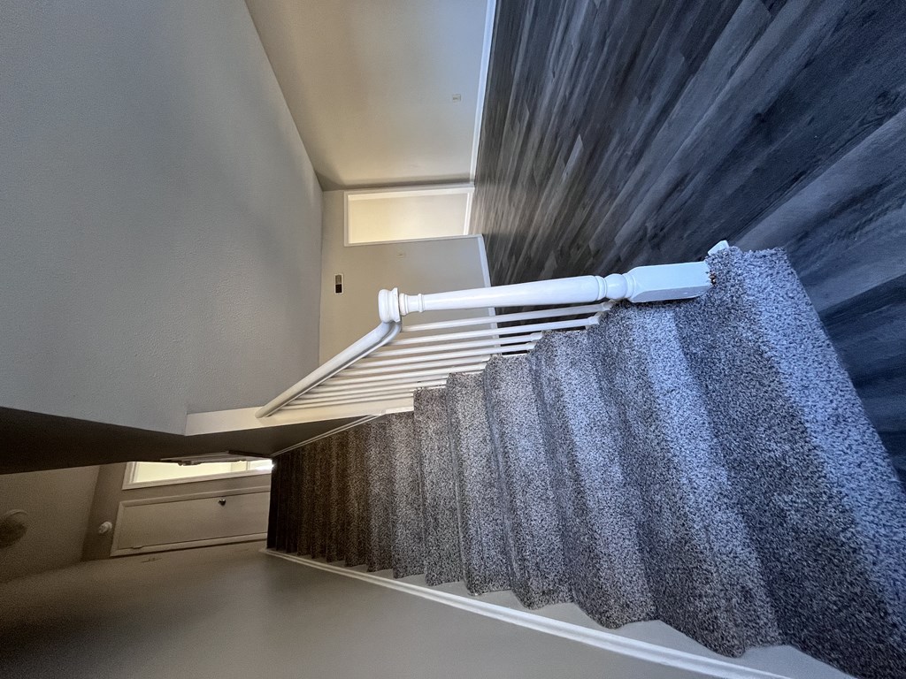 A staircase with a grey carpeted runner and white handrail.