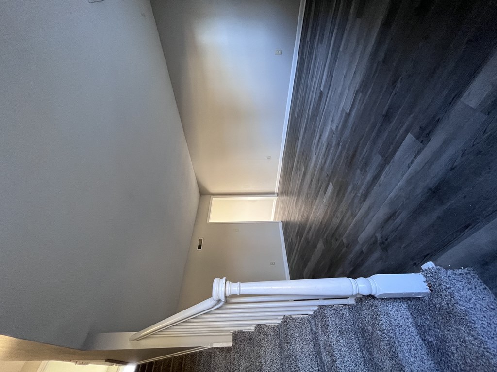 A staircase with a grey carpeted runner and white balusters.