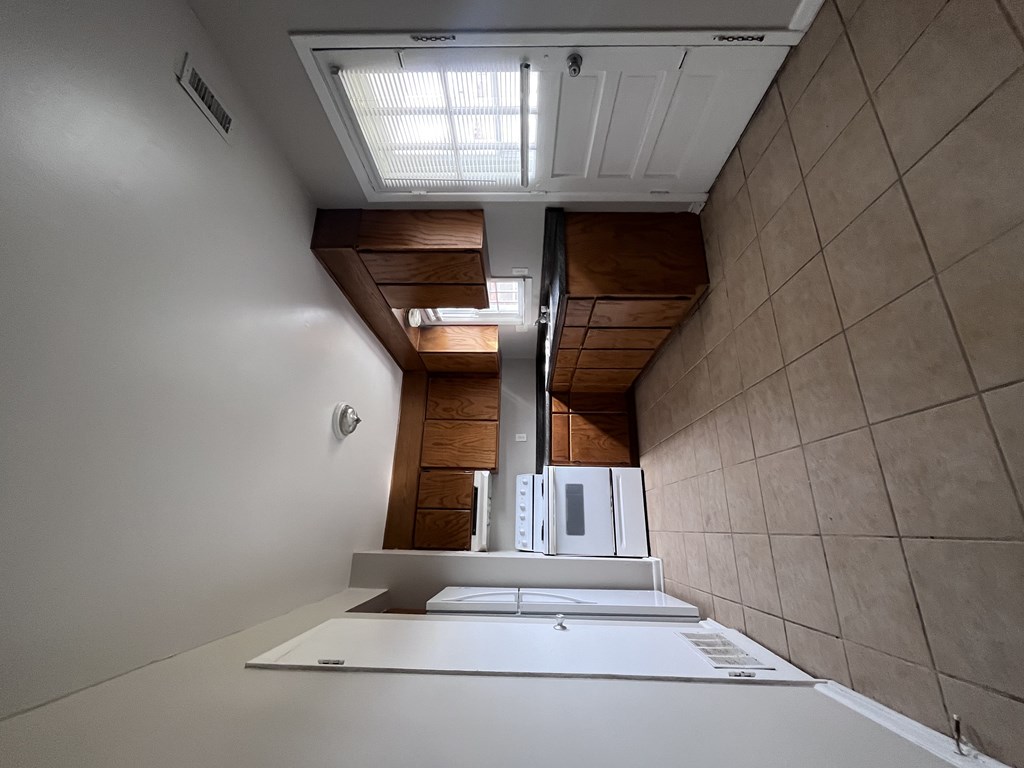 A modern kitchen with a white countertop and a staircase leading to the upper level.