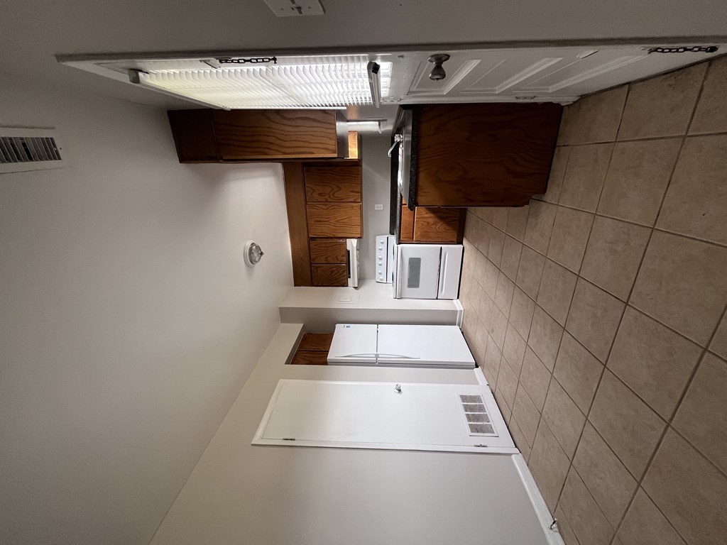 A kitchen with white appliances and wooden cabinets.