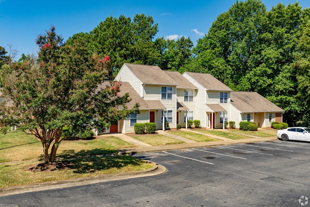 A white car is parked in front of a building with a red door.