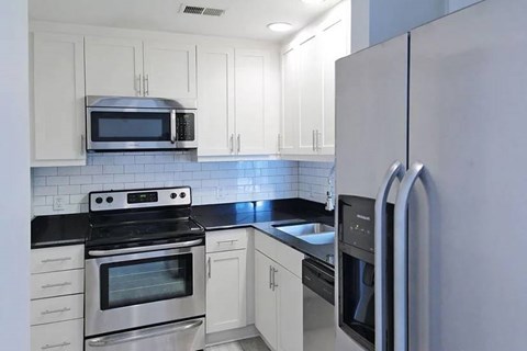 A kitchen with white cabinets and a black countertop.