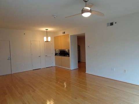A room with a ceiling fan and wooden floors.