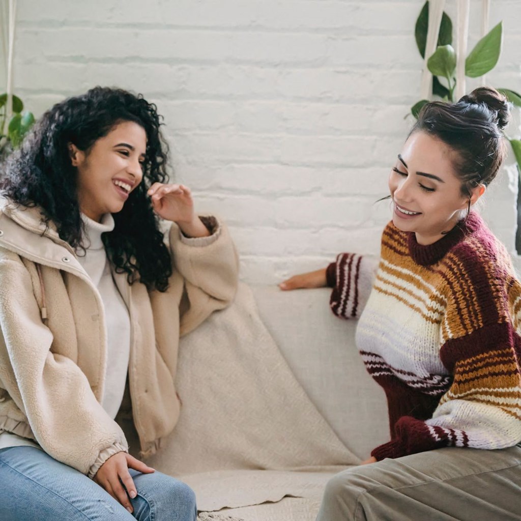 two women sitting on a couch laughing