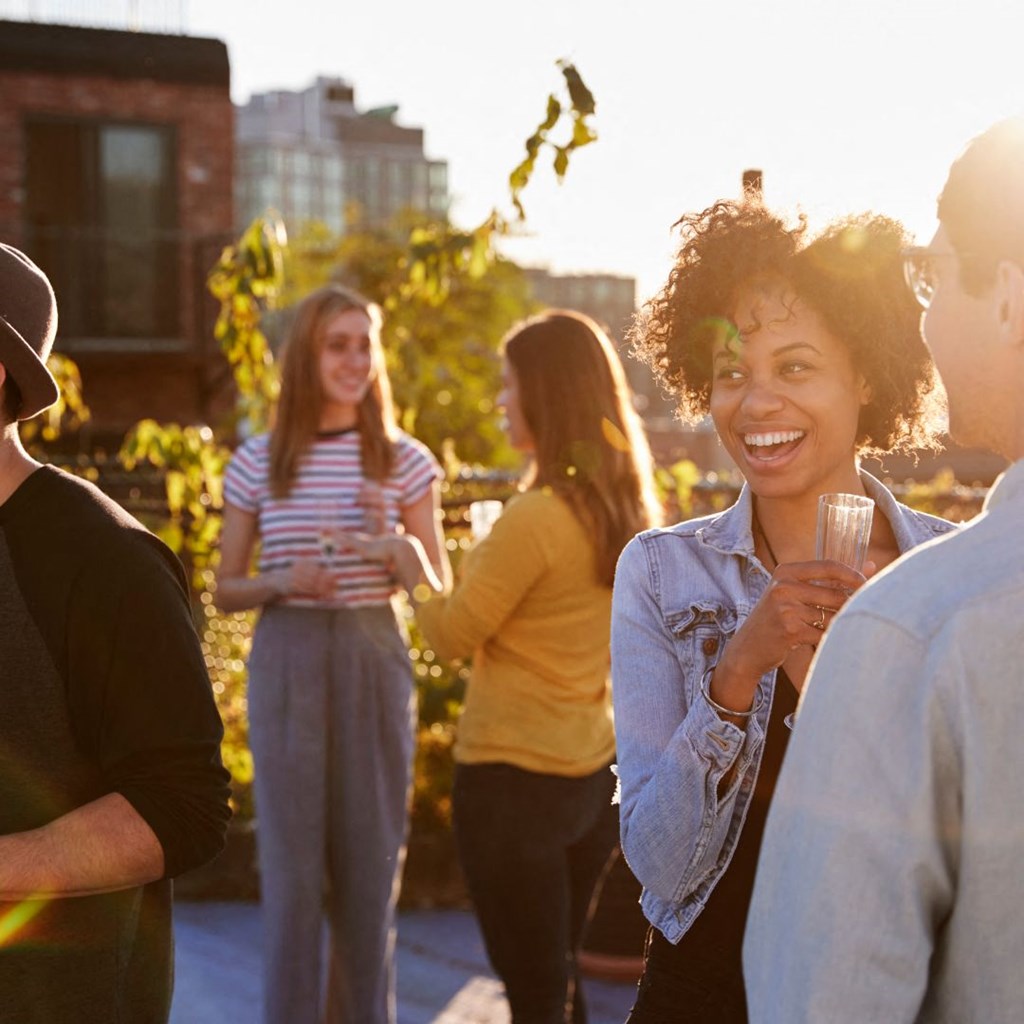 a group of people standing around talking and drinking wine