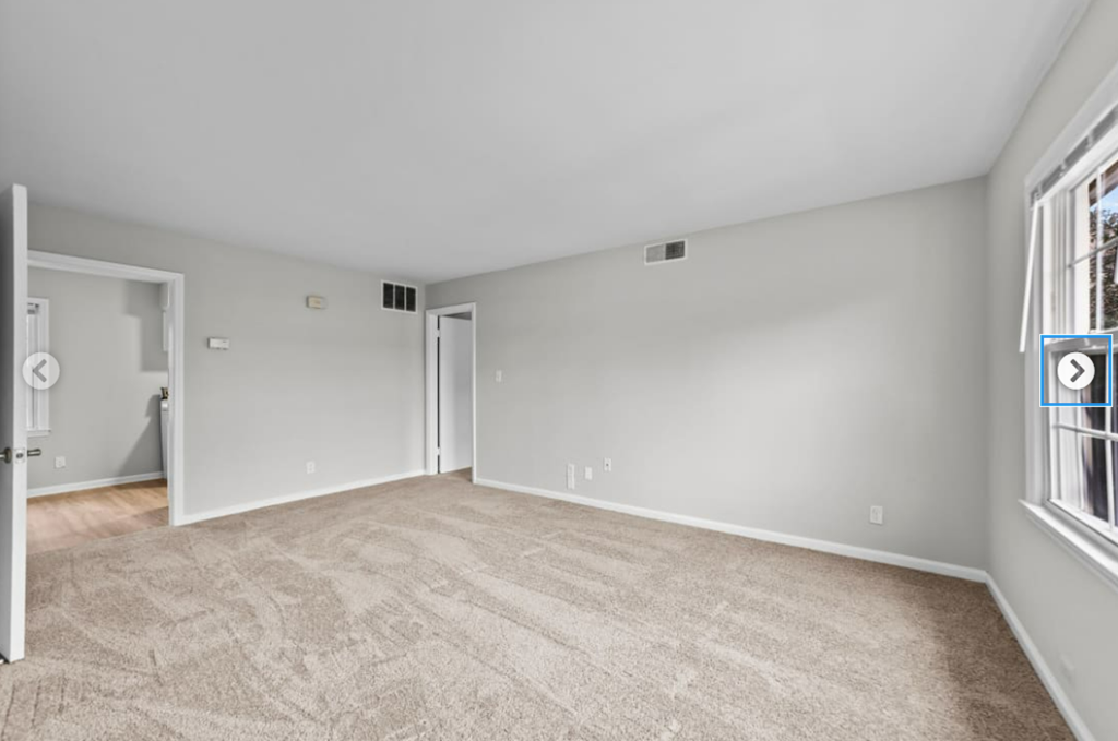 an empty living room with a door to a hallway