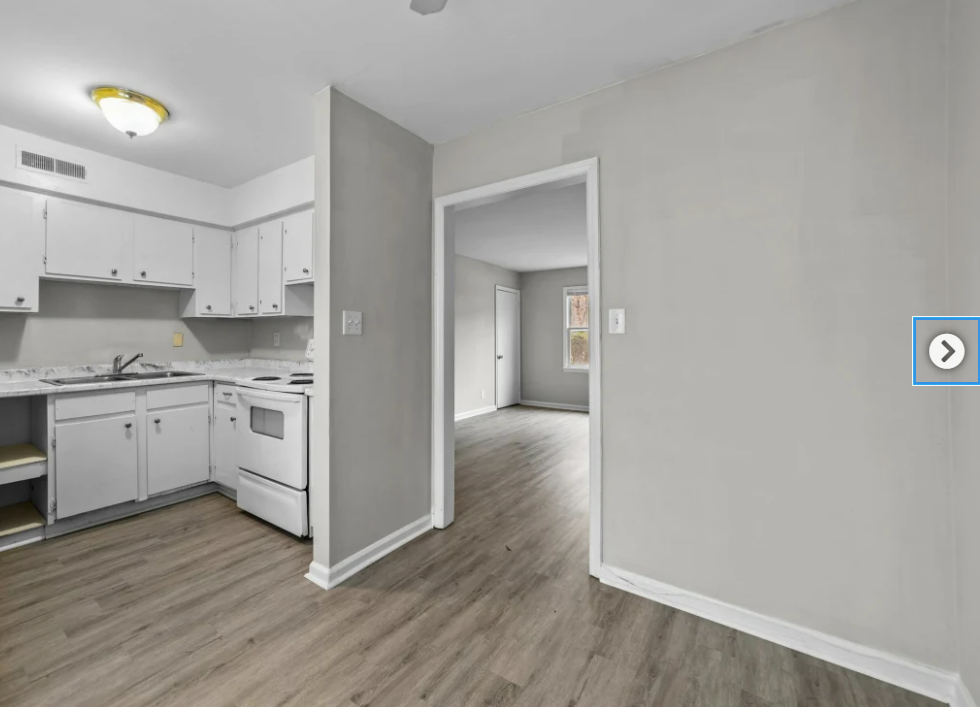 an empty kitchen and living room with white cabinets and white appliances