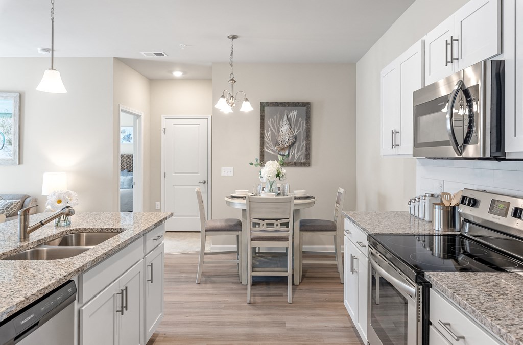 a kitchen and dining room with granite counter tops and white cabinets