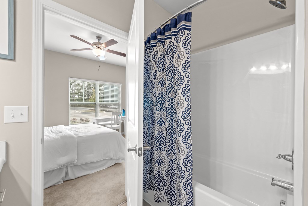 a bedroom with a bed and a shower and a ceiling fan