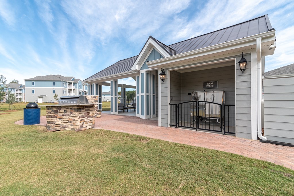 a patio with a grill and a house with a yard